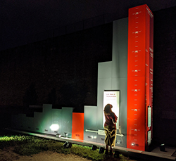 A historic site visitor standing at the base of a 3D bar graph and looking up at the 16-foot tall column representing 2010 US rate of incarceration