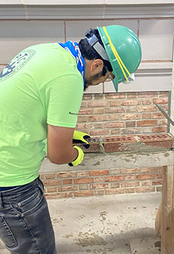 student participating in a masonry workshop at Eastern State Penitentiary, learning bricklaying technique