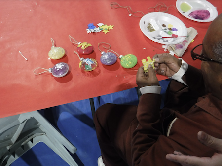 Homemade Christmas ornaments on a red tablecloth, the rear of a person's head