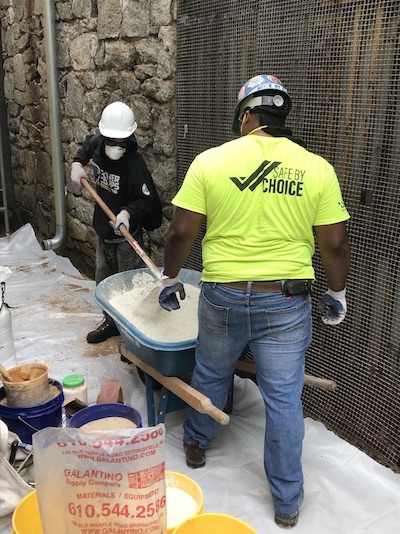 Masonry workshop participants work at a wheelbarrow.