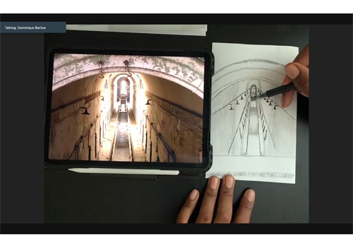 a person's hands sketching an Eastern State cellblock from a photo