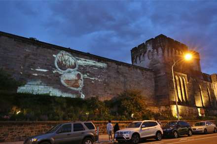 Image of a heart shaped locket projected on the facade of Eastern State at night